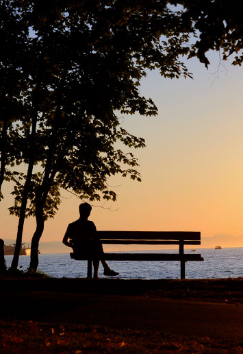 person sitting on bench at sunset